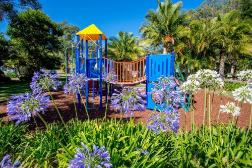 a playground in a garden with purple flowers at Ingenia Holidays Lake Macquarie in Mannering Park