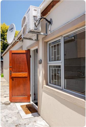 a house with a wooden door and a window at A Room with private Entrance in Cape Town