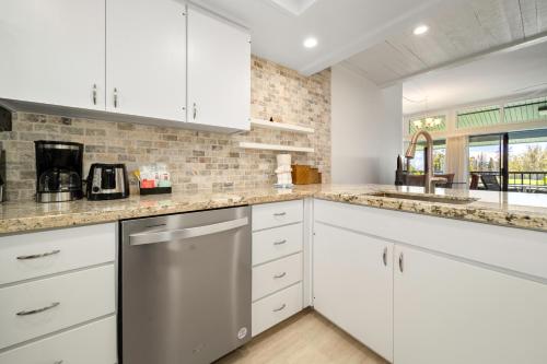 a kitchen with white cabinets and marble counter tops at Kapalua Villas Maui - Select Your Unit in Kahana