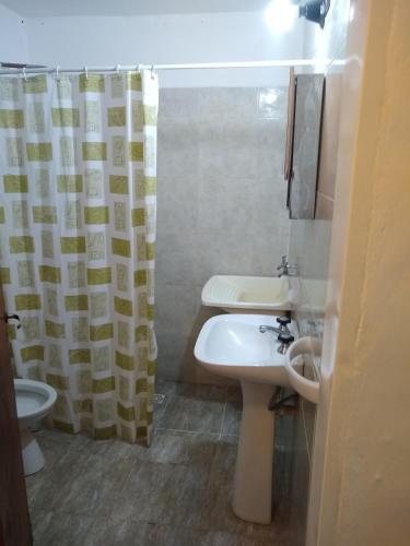 a bathroom with a sink and a toilet and a shower curtain at Complejo Viejo Sulky in Mina Clavero