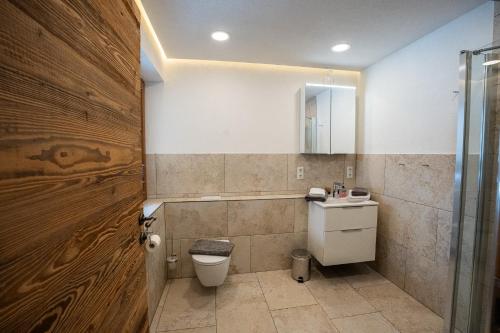 a bathroom with a toilet and a wooden door at Schickster Sky Lodge in Leutasch