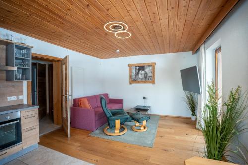 a living room with a purple couch and wooden ceiling at Schickster Sky Lodge in Leutasch
