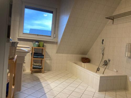 a white bathroom with a tub and a window at HofamHohlebach in Neuenburg am Rhein