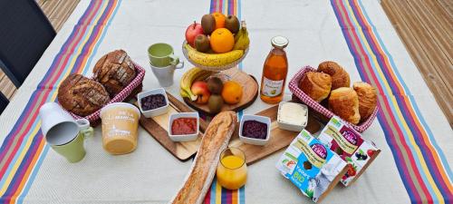 une table avec du pain et des fruits et des bouteilles de jus d'orange dans l'établissement Le Jardin des 2 Cèdres, à Isigny-le-Buat