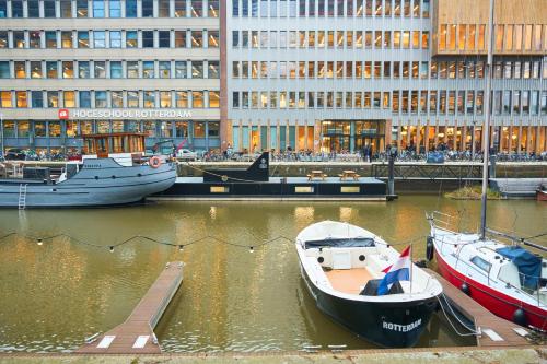 a group of boats docked in a marina with a building at De Coaster & Aquarium Ponton in Rotterdam