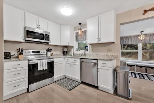 a kitchen with white cabinets and stainless steel appliances at Charming Cape Cod Retreat in Bourne in Bourne