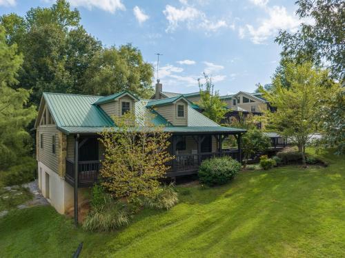 a house with a green roof and a yard at Lodge At Tellico in Tellico Plains