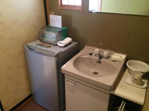 a small bathroom with a sink and a refrigerator at Yudanaka Onsen Yamazakiya in Yamanouchi
