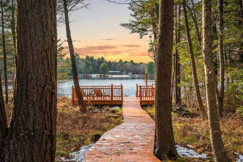 a wooden bridge over a body of water with trees at Lakeview Sunset Heaven Waterfront Escape Private Dock Firepit Game Room New Construction in Blakeslee