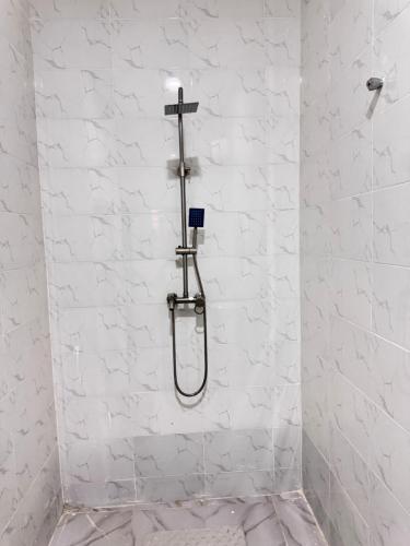 a shower in a white bathroom with a cross on the wall at Sunny Service Apartment in Lagos