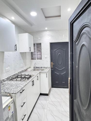 a kitchen with white cabinets and a black door at Sunny Service Apartment in Lagos
