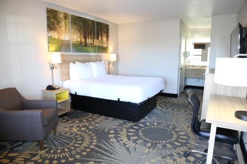 a hotel room with a bed and a chair at Days Inn by Wyndham Monroe, Louisiana in Monroe