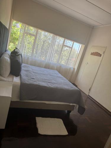 een slaapkamer met een bed voor een raam bij Calenstel in Bulawayo