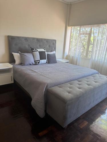 een slaapkamer met een groot bed met kussens en een raam bij Calenstel in Bulawayo
