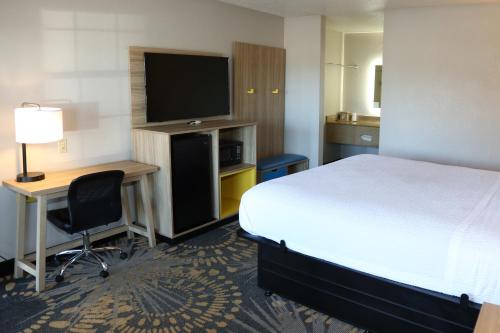 a hotel room with a bed and a desk and a television at Days Inn by Wyndham Monroe, Louisiana in Monroe
