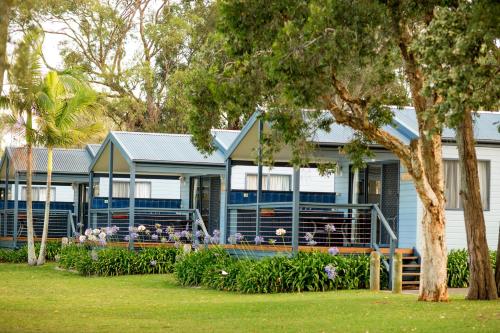 a blue house with people sitting on the porch at Ingenia Holidays Lake Macquarie in Mannering Park