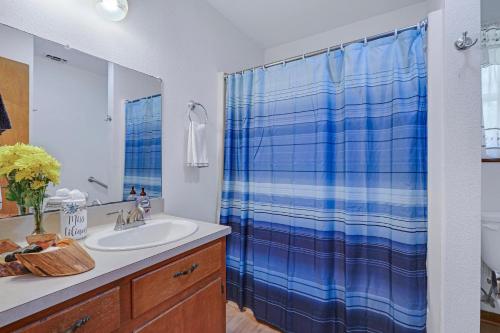a bathroom with a sink and a blue shower curtain at Miss Lilian's House in Wimberley