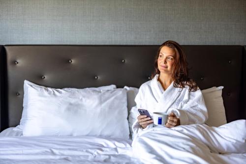a woman laying in bed holding a cell phone at Melrose Georgetown Hotel in Washington