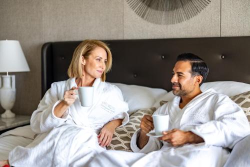 a man and woman sitting in bed drinking coffee at Melrose Georgetown Hotel in Washington