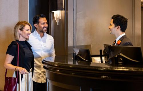 a woman and two men standing in front of a desk at Melrose Georgetown Hotel in Washington