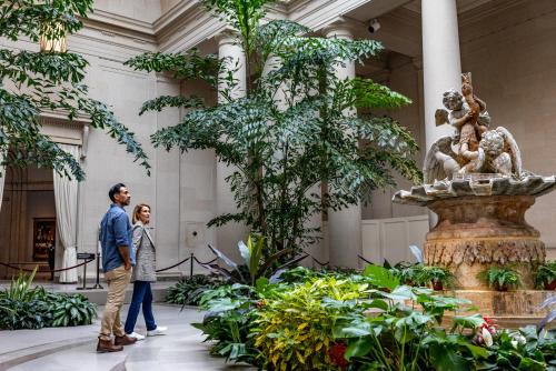 a man and woman walking through the lobby of a building with a fountain at Melrose Georgetown Hotel in Washington