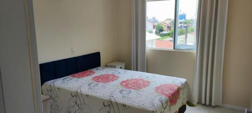 a bedroom with a bed with a quilt on it at Apartamento 202 Bombinhas in Bombinhas