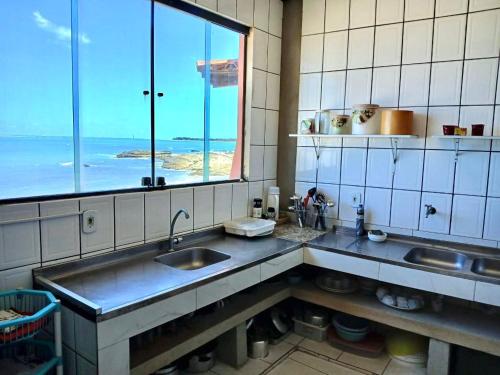 a kitchen with a sink and a large window at O De Casa in Japaratinga
