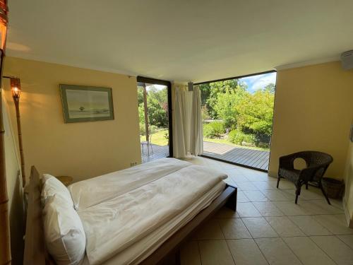 a bedroom with a large bed and a large window at Basco River Lodge Holiday Villa in Grabouw