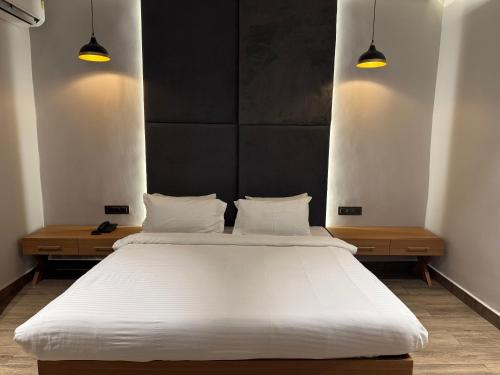 a bedroom with a large white bed with two lights at The Beach House Candolim in Candolim