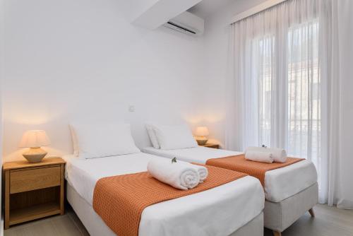 two beds in a white room with a window at BeachSide Escape Apartments in Psili Ammos