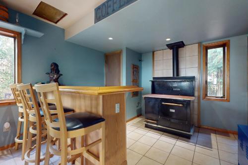 a kitchen with a stove and a bar with chairs at Hawk's Hole in Hansville
