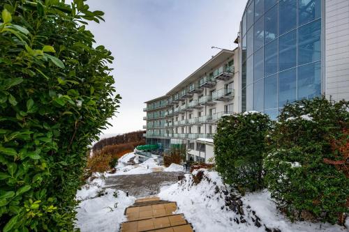 a building with snow in front of it at Hotel Ózon & Luxury Villas in Mátraháza