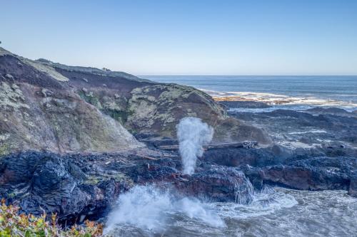 a pipe spewing out water onto a rocky beach at The Boat House in Yachats