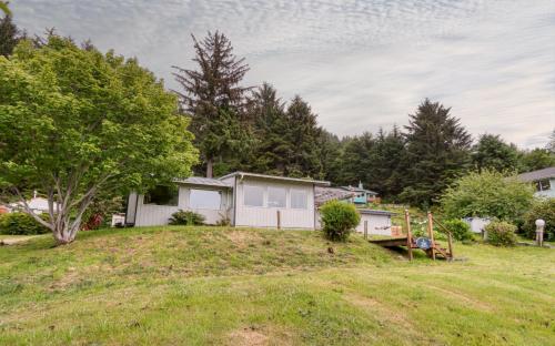 an open yard with a house and trees at The Boat House in Yachats