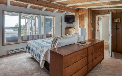 a bedroom with a bed with a dresser and a window at The Boat House in Yachats