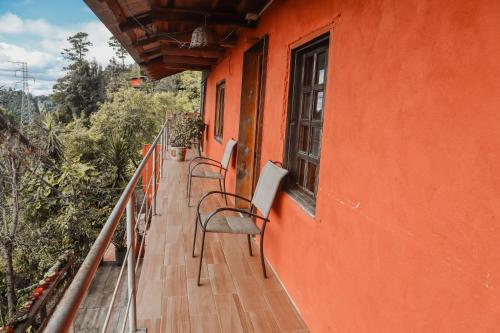 an orange building with chairs on a balcony at San José del Pacífico- Cabañas Camino al Cielo 4 in El Pacífico