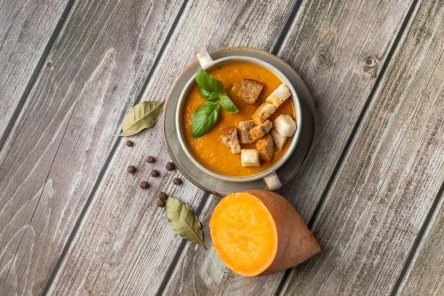 a bowl of soup and an orange slice on a wooden table at Hotel Rzemieślnik Zakopane in Zakopane