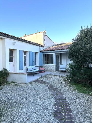 une maison avec deux bancs et une allée en gravier dans l'établissement Au calme proche de La Rochelle, de la mer et du golf, à Nieul-sur-Mer