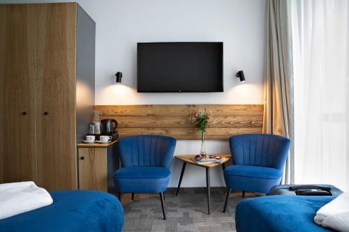 a hotel room with two blue chairs and a tv at Hotel Rzemieślnik Zakopane in Zakopane