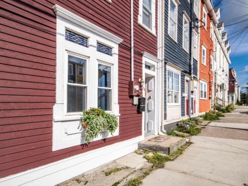 a red building with a window on a street at Historic Jelly Bean Row House Walk to Signal Hill in St. John's