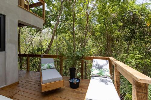 a deck with two chairs and a balcony with trees at Villa Sea Breeze in West End