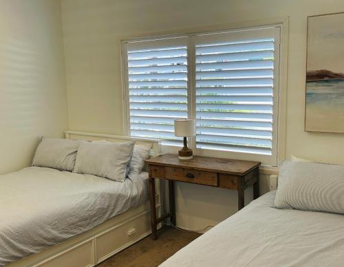 Un dormitorio con dos camas y una mesa con lámpara. en Bahia by the Beach, en Avoca Beach