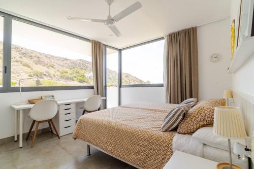 Un dormitorio con una cama y un escritorio y ventanas. en Exclusiva casa con encanto en Agua Amarga, en Agua Amarga