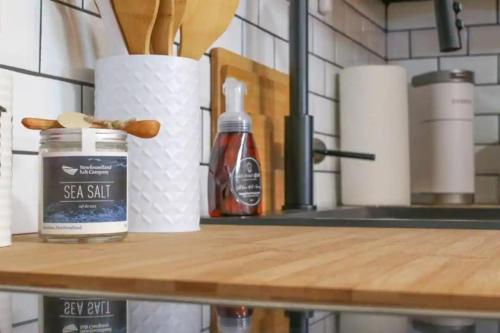 a counter top with a table with a bottle of soy salt and paper towels at Queens Suite 1bdrm in St. John's