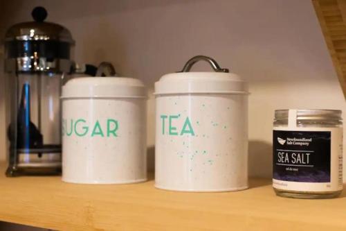 three white canisters sitting on a shelf at Queen Loft 2br in St. John's