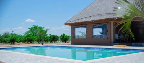 a resort with a swimming pool and a hut at Kuswani Hotel in Sebina