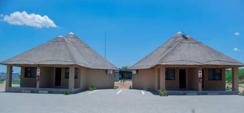 two buildings with thatched roofs in a parking lot at Kuswani Hotel in Sebina