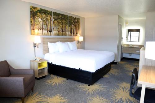 a hotel room with a bed and a chair at Days Inn by Wyndham Monroe, Louisiana in Monroe