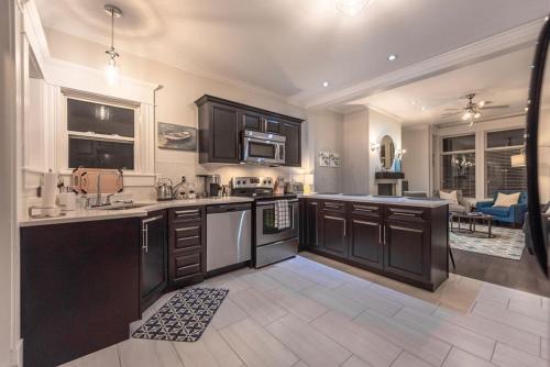 a kitchen with black cabinets and a living room at Blvd House Quidi Vidi Lake Parking in St. John's