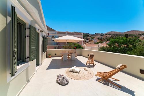 a balcony with a table and chairs and an umbrella at Nisomar Suites in Symi
